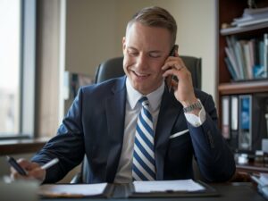 Businessman writing notes while speaking on the phone.