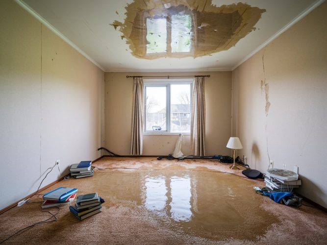 Room with severe water damage, including a large hole in the ceiling and flooded carpet.